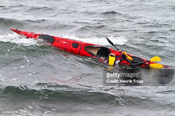 man with capsized kayak - sea kayak stock pictures, royalty-free photos & images