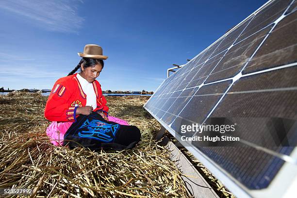 peruvian woman of the uros islands, lake titicaca, with solar panel. puno, peru. - zonne eiland stockfoto's en -beelden