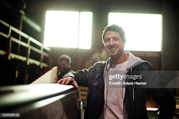 man posing while his college is unloading plunks from back of pickup truck - pick up truck back stock-fotos und bilder