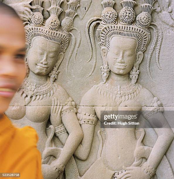 buddhist monk walking by relief sculpture - hugh sitton - fotografias e filmes do acervo