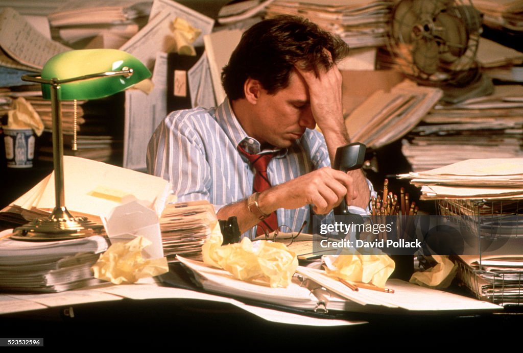 Stressed businessman surrounded by paperwork