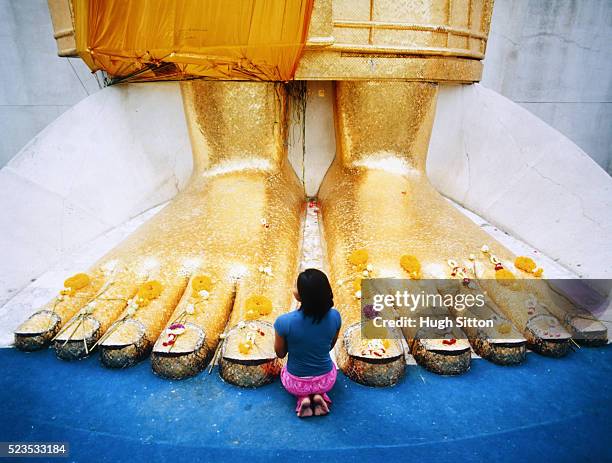 young woman praying at feet of giant buddha statue - hugh sitton - fotografias e filmes do acervo