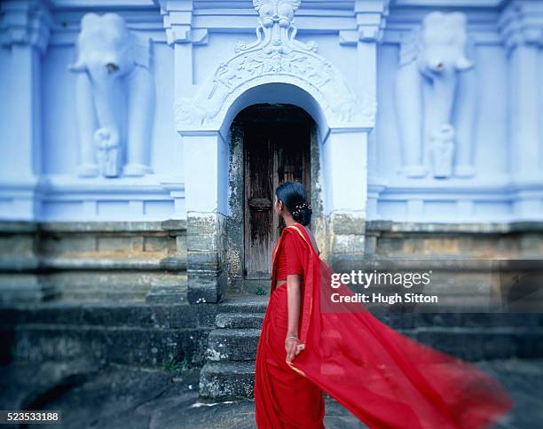 woman in red clothes in front of temple, sri lanka - woman in red sari stock-fotos und bilder