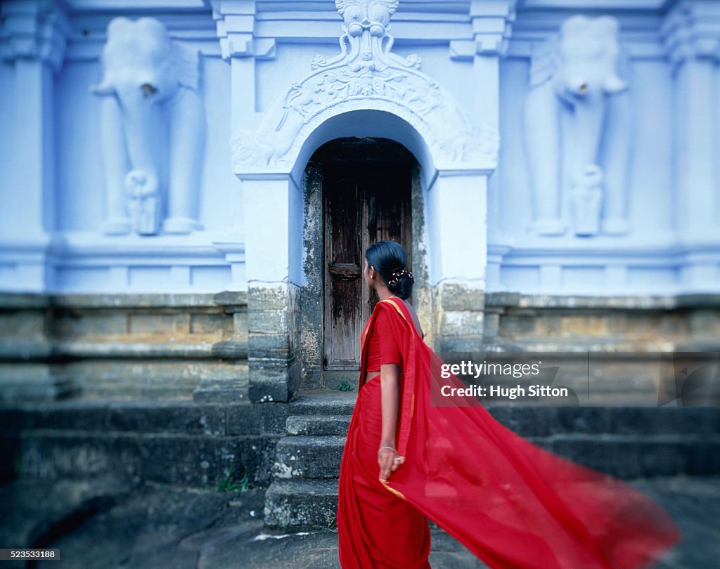 Woman in red clothes in front of temple, Sri Lanka