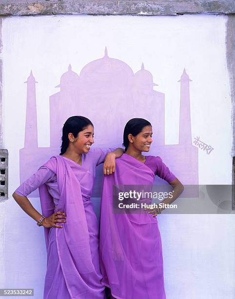 two young women in front of mural painting of taj mahal wearing sari, india - hugh sitton india stockfoto's en -beelden