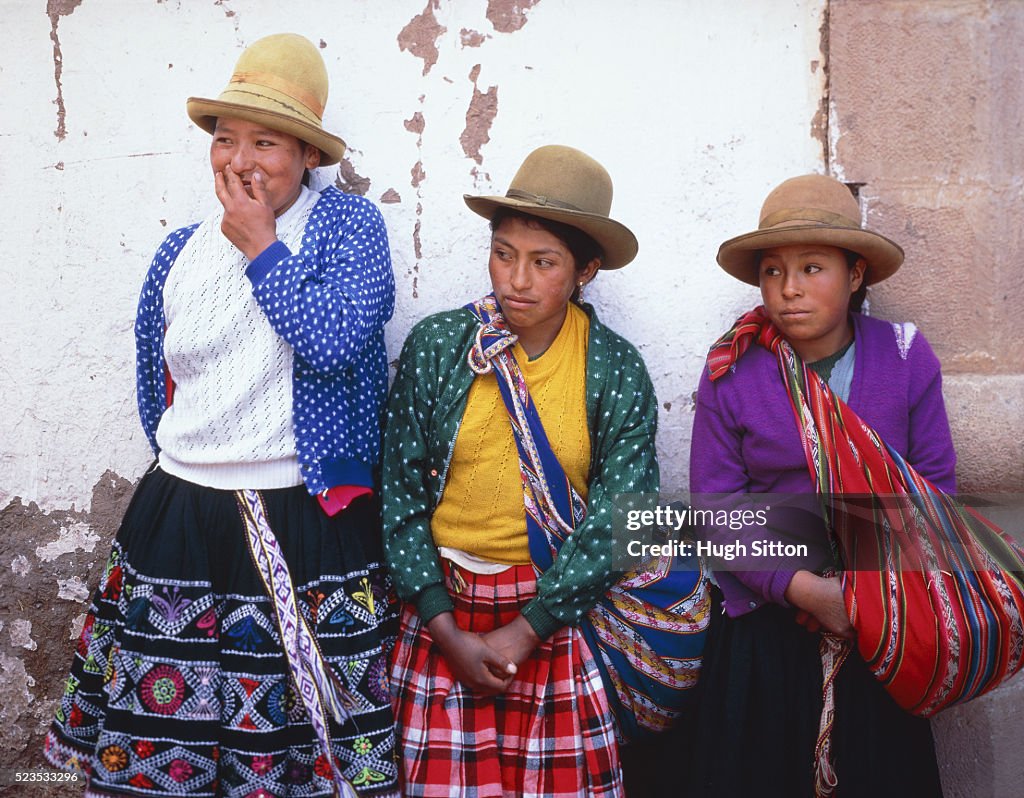 Three young peruvian woman leaning on a wall, Peru, Cusco