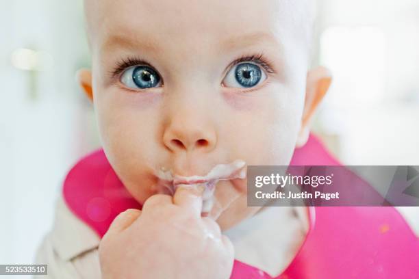 messy baby face - closeup - baby eating yogurt stockfoto's en -beelden