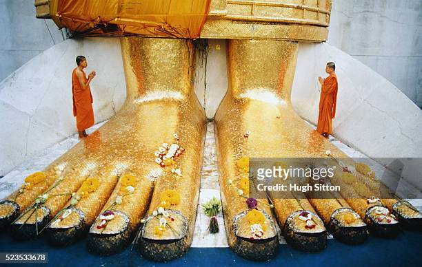 two buddhist monks praying by giant buddha statue - hugh sitton stock pictures, royalty-free photos & images
