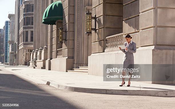 woman on the sidwalk using a tablet - electronic organizer stock pictures, royalty-free photos & images