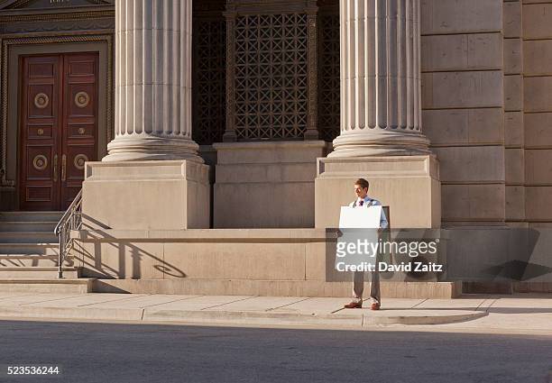 man wearing a sandwich board on the sidewalk - plakkaat stockfoto's en -beelden
