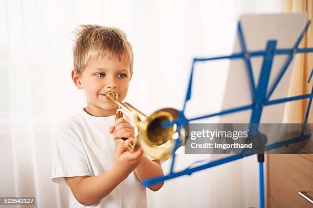 little boy practicing playing trumpet - blaasinstrument stockfoto's en -beelden