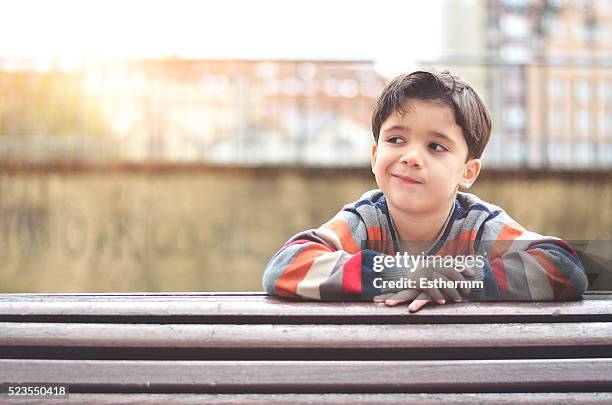 thoughtful boy sitting on a bench - boy thoughtful stock-fotos und bilder