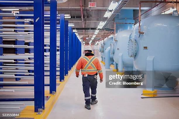 Worker walks past large plate frame heat exchangers at the Enwave Energy Corp. Pumping station in Toronto, Ontartio, Canada, on Friday, April 8,...