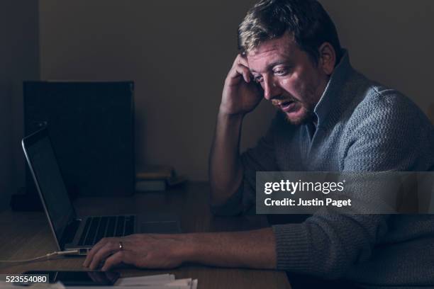 sad man at home desk - hombre llorando fotografías e imágenes de stock