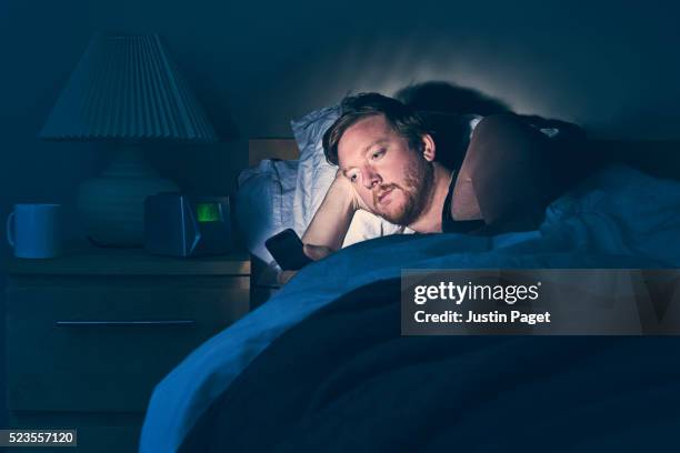 male using smartphone in bed at night - vice after dark stock pictures, royalty-free photos & images