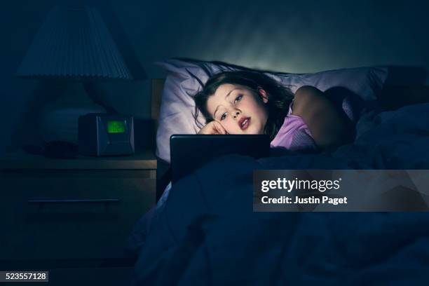 young girl using tablet in bed - bed tablet stock pictures, royalty-free photos & images