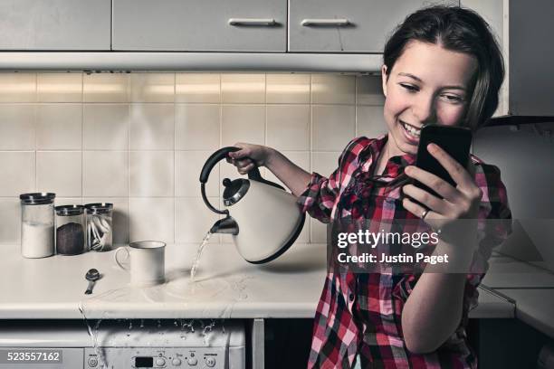 teenage girl on phone whilst pouring kettle - misfortune concept stock pictures, royalty-free photos & images