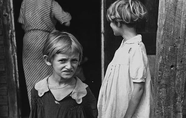 Bức ảnh chụp hai cô gái trẻ là con của một người nông dân, họ mặc quần áo đơn giản có dấu hiệu đã cũ, có thể nhìn thấy mẹ của họ...