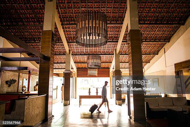 a man walking through the lobby of a hotel with a suitcase. - suitcase hotel stock pictures, royalty-free photos & images