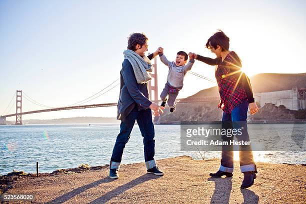 two moms playing with son (2-3) in front of golden gate bridge, san francisco, california, usa - lesbische stock-fotos und bilder
