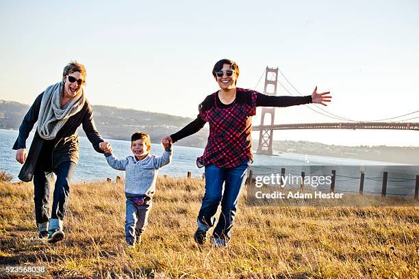 two moms walking with son (2-3) in front of golden gate bridge, san francisco, california, usa - golden gate bridge stock pictures, royalty-free photos & images