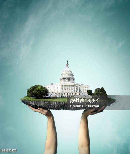 u.s. capitol building on chunk of land being held up by hands - the u s capitol in washington dc stock-fotos und bilder