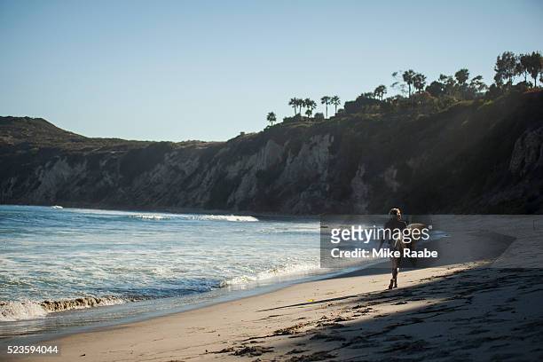 young woman walking on beach, malibu, california, usa - malibu foto e immagini stock