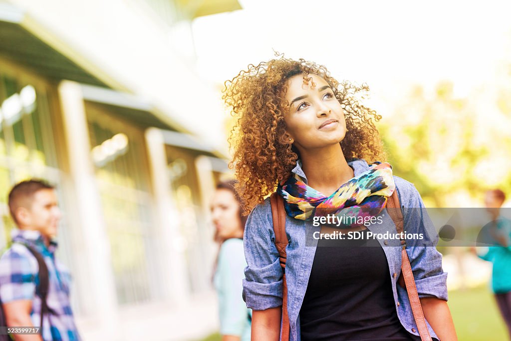 Cute college student walking around campus on sunny day