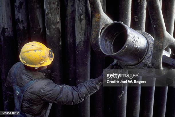 oil worker adjusting well pipe - vintage oilfield stock-fotos und bilder