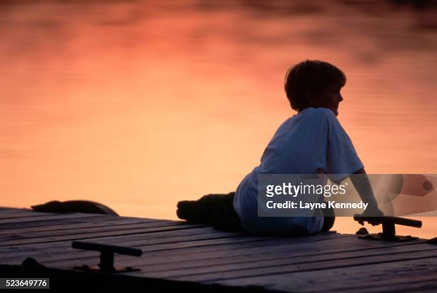 boy sitting on a dock at sunset - isle royale national park - fotografias e filmes do acervo