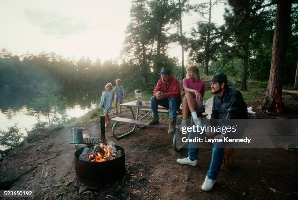 sitting around campfire by lake - archival camping stock pictures, royalty-free photos & images