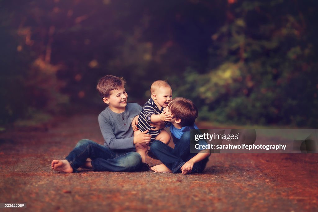Three brothers laughing together on forest path