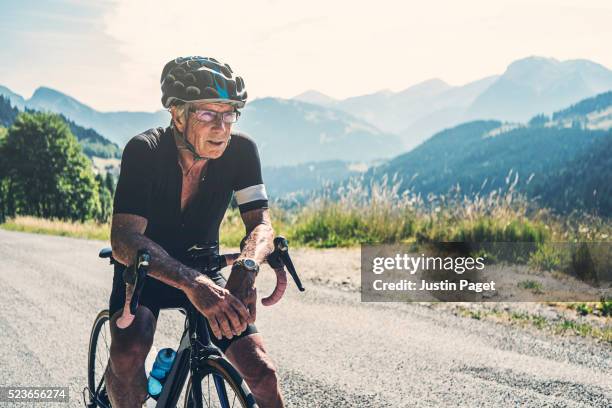 senior male resting on handlebars - senior sport stockfoto's en -beelden