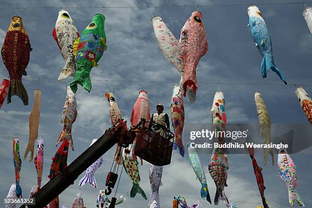 Man stands on a crain as he prepares to hoist colorful Koinobori or carp streamers over the Akutagawa river at Akutagawa Sakurazutumi Park, on April...