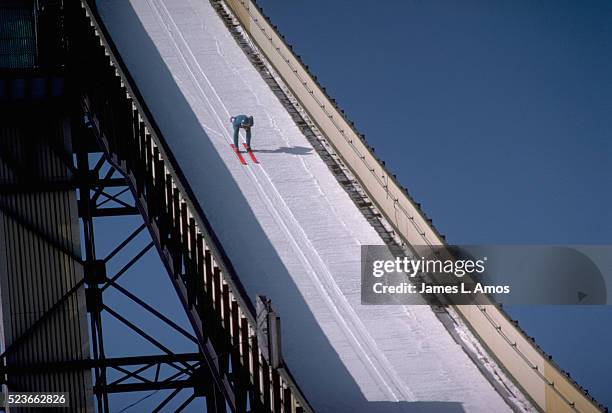 ski jumper skiing down ski jump ramp - ski jumping stock-fotos und bilder