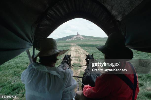 pioneers approaching chimney rock - planwagen stock-fotos und bilder