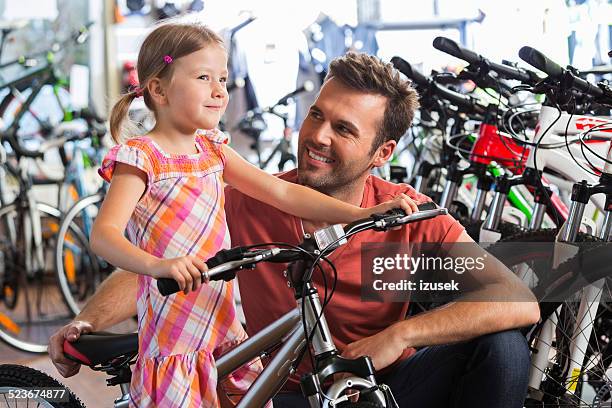 father with little daughter in bike store - buying a bike bildbanksfoton och bilder