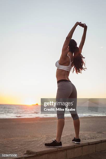 young woman stretching on beach at sunset - manhattan beach stockfoto's en -beelden