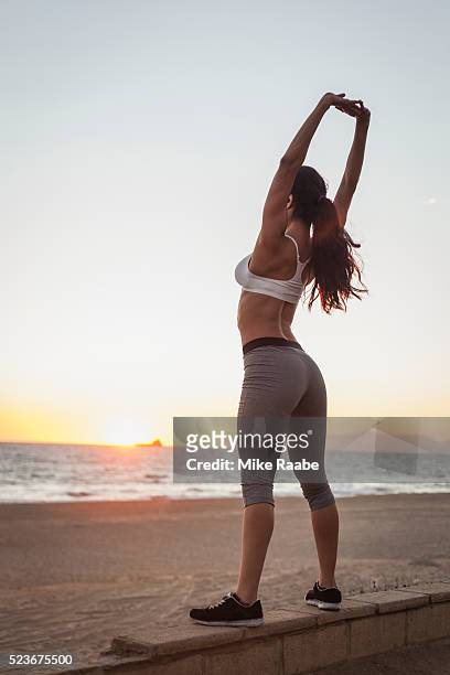 young woman stretching on beach at sunset - manhattan beach stock pictures, royalty-free photos & images