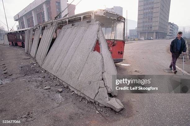 Damaged barricade made from concrete and old streetcars blocks a portion of a street in Sarajevo, Bosnia to allow residents a safe passage. The area...