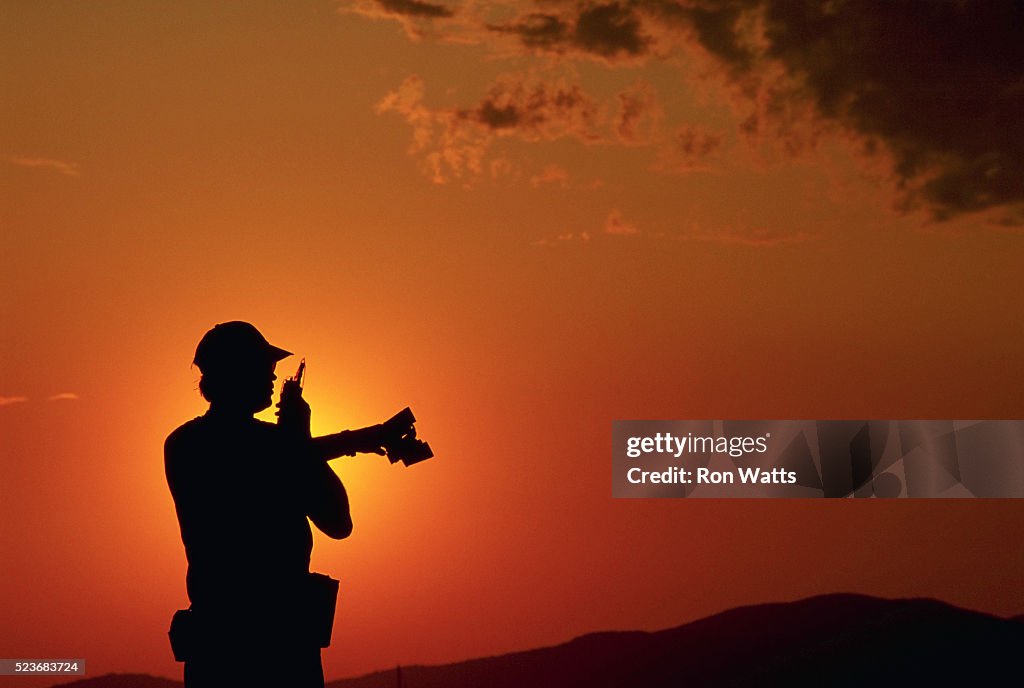 Silhouetted Lifeguard Talking on Walkie-Talkie