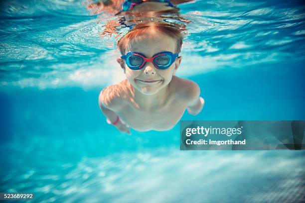 kleiner junge schwimmen unter wasser im pool - schwimmen schwimmbad stock-fotos und bilder