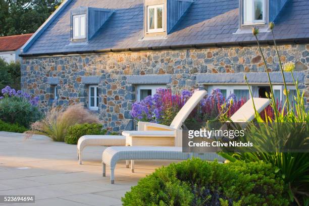 le haut, guernsey: border by swimming pool with deck chairs, stipa tenuissima and campanula - stipa stock pictures, royalty-free photos & images