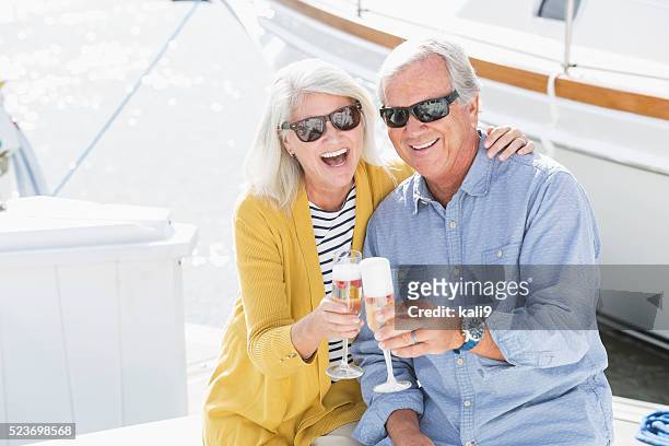 senior couple on boat celebrating with champagne - bonding stock pictures, royalty-free photos & images