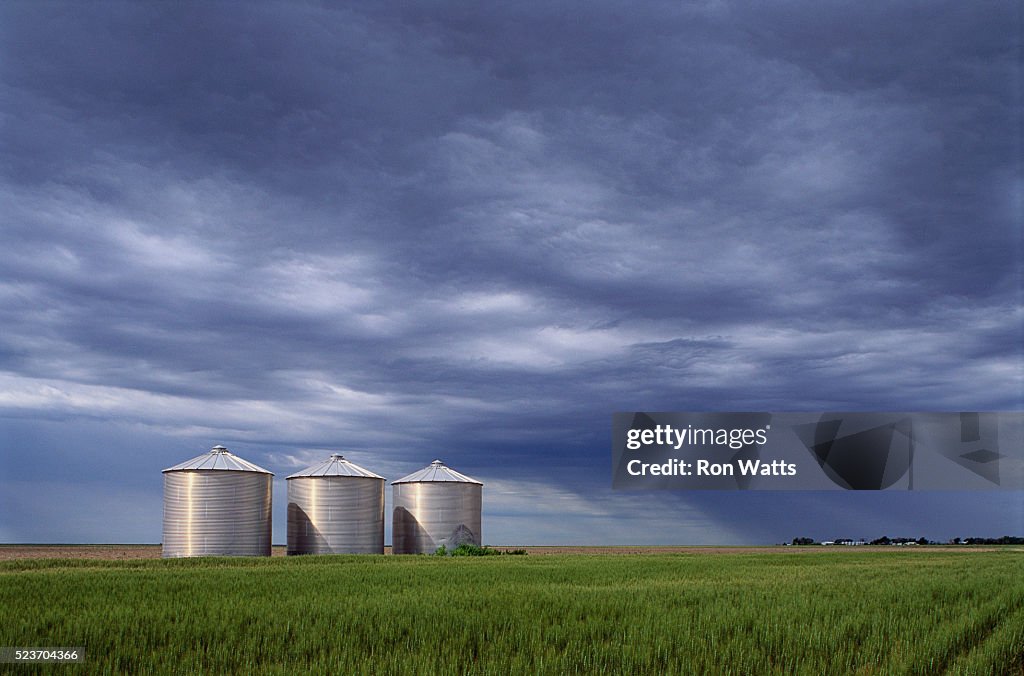 Silos in a Field Under Cloudy Skies