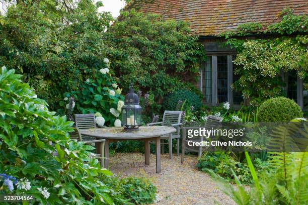 woolstone mill house, oxfordshire: seating area with table & chairs with white-flowered theme.schizo - courtyard garden stockfoto's en -beelden