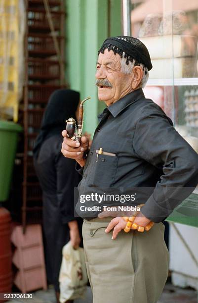 man smoking a pipe and holding amber worry beads - greek worry beads stock pictures, royalty-free photos & images