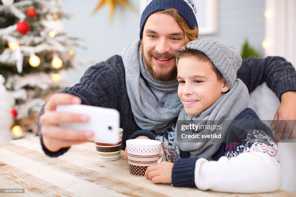 Father and son taking selfies outdoors.