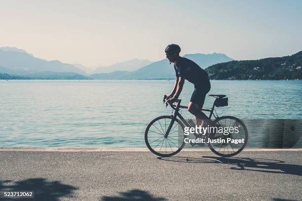 cyclist by lake annecy, france - annecy stock-fotos und bilder