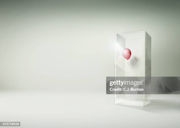 pink balloon floating in side of a tall glass box - barriere stock-fotos und bilder